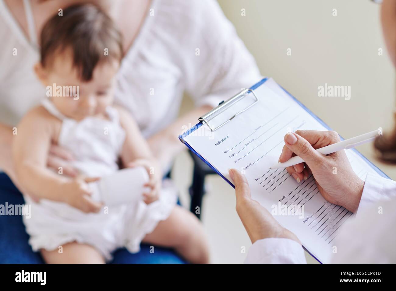Kinderarzt füllt medizinisches Dokument aus Stockfoto