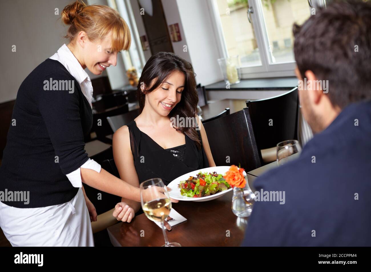 Kellnerin mit Salat serviert eine Frau im Restaurant Stockfoto