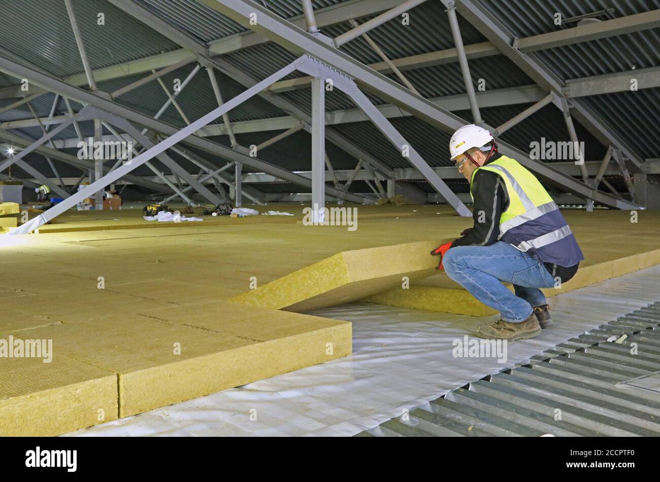 Ein Arbeiter legt Isolationsplatten im Dachbereich einer großen Industrieanlage in East London, Großbritannien. Stockfoto