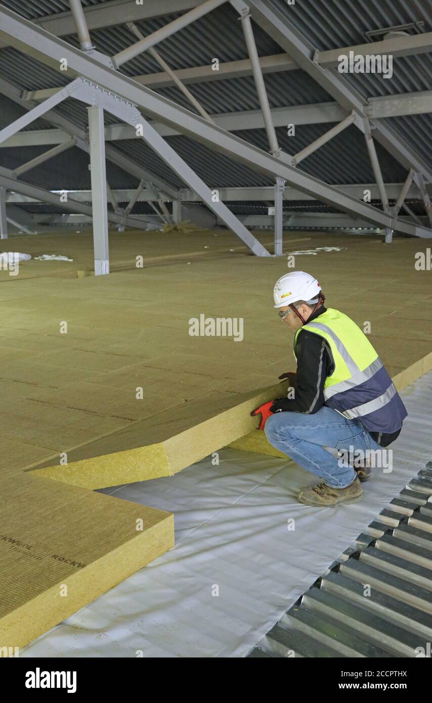 Ein Arbeiter legt Isolationsplatten im Dachbereich einer großen Industrieanlage in East London, Großbritannien. Stockfoto
