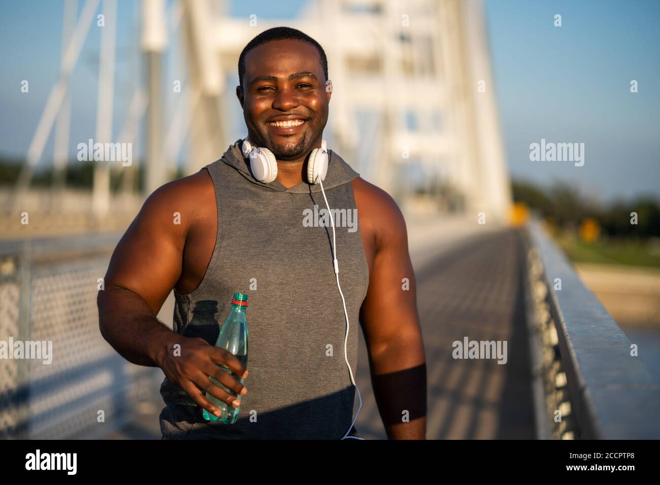 Porträt eines jungen fröhlichen afroamerikanischen Mannes in Sportkleidung, der auf die Kamera schaut und lächelt. Stockfoto