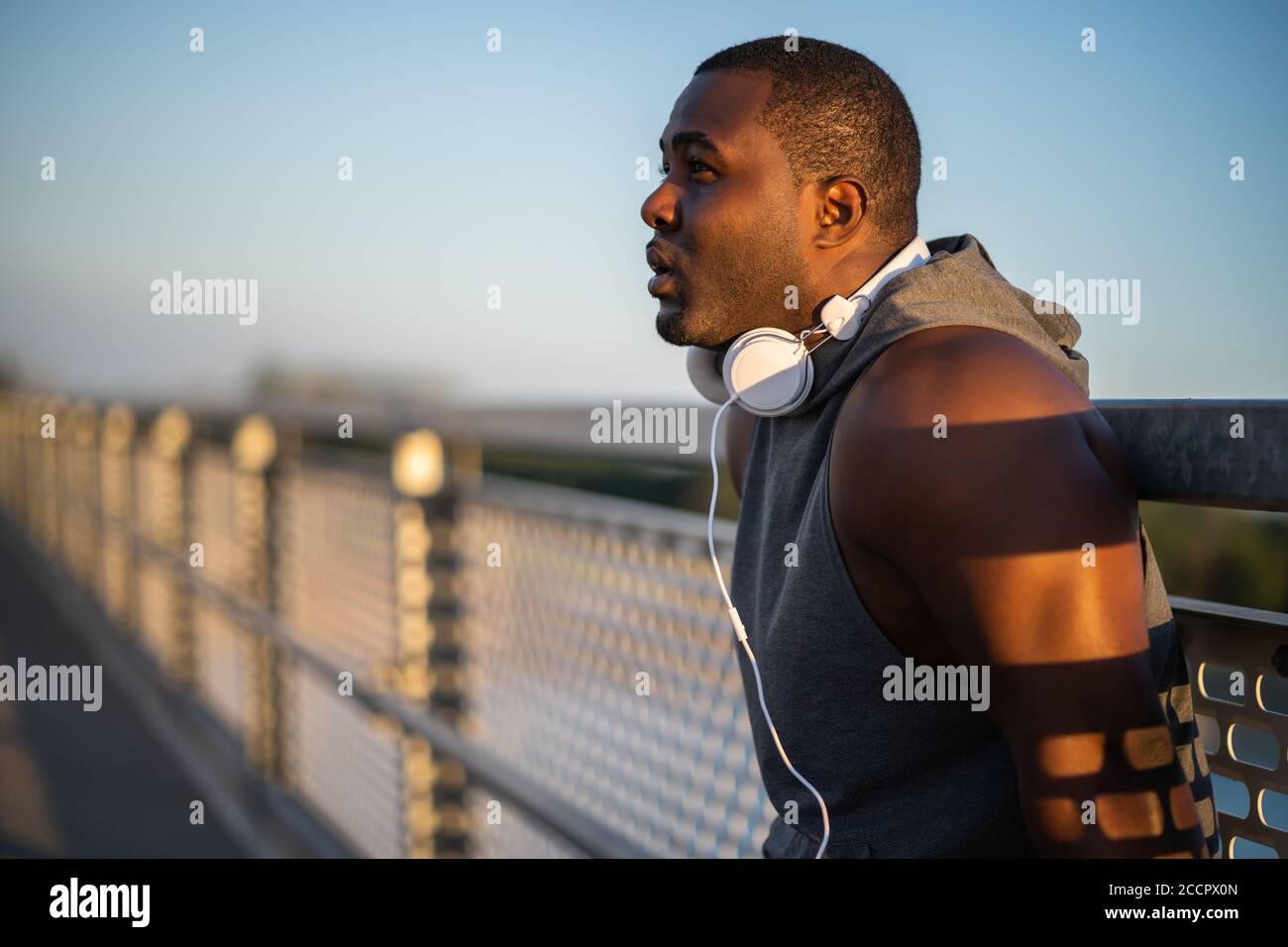 Porträt eines jungen fröhlichen afroamerikanischen Mannes in Sportkleidung, der sich nach dem Joggen entspannt. Stockfoto