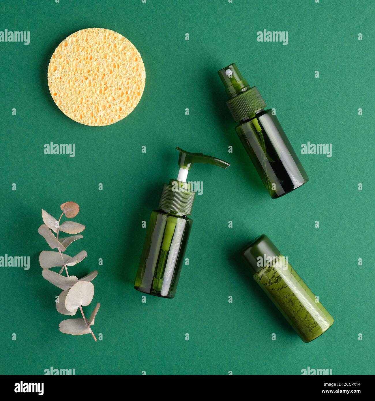 Flach liegend, Draufsicht grüne Kosmetikflaschen, Schwamm, Eukalyptusblatt auf grünem Hintergrund. Natürliche Bio-Beauty-Produkte Set. Beauty- und Spa-Konzept. Stockfoto
