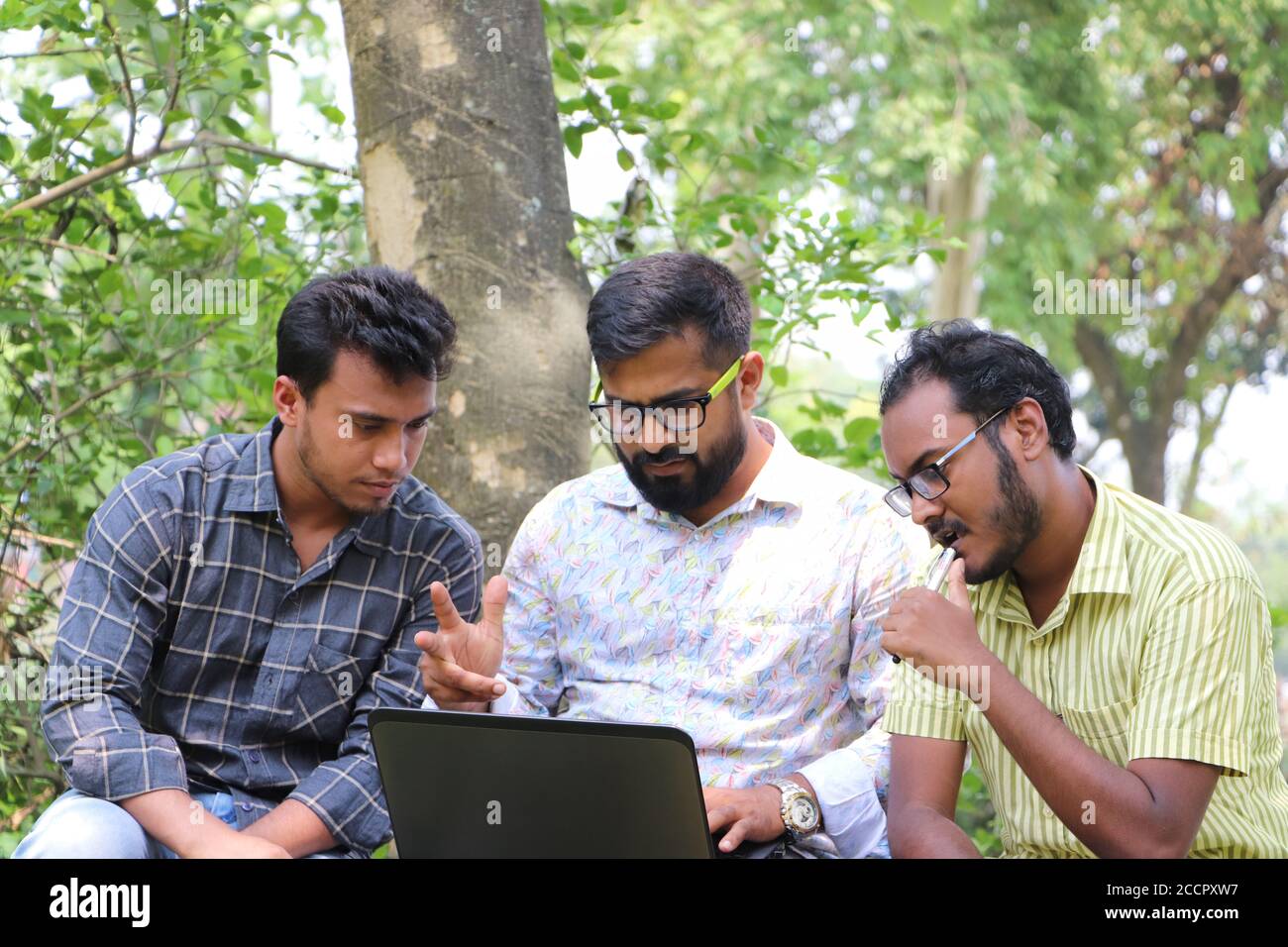 Zwei asiatische Studenten arbeiten an einem Forschungsprojekt auf Laptop Mit ihrem Mentor auf dem College-Campus Stockfoto