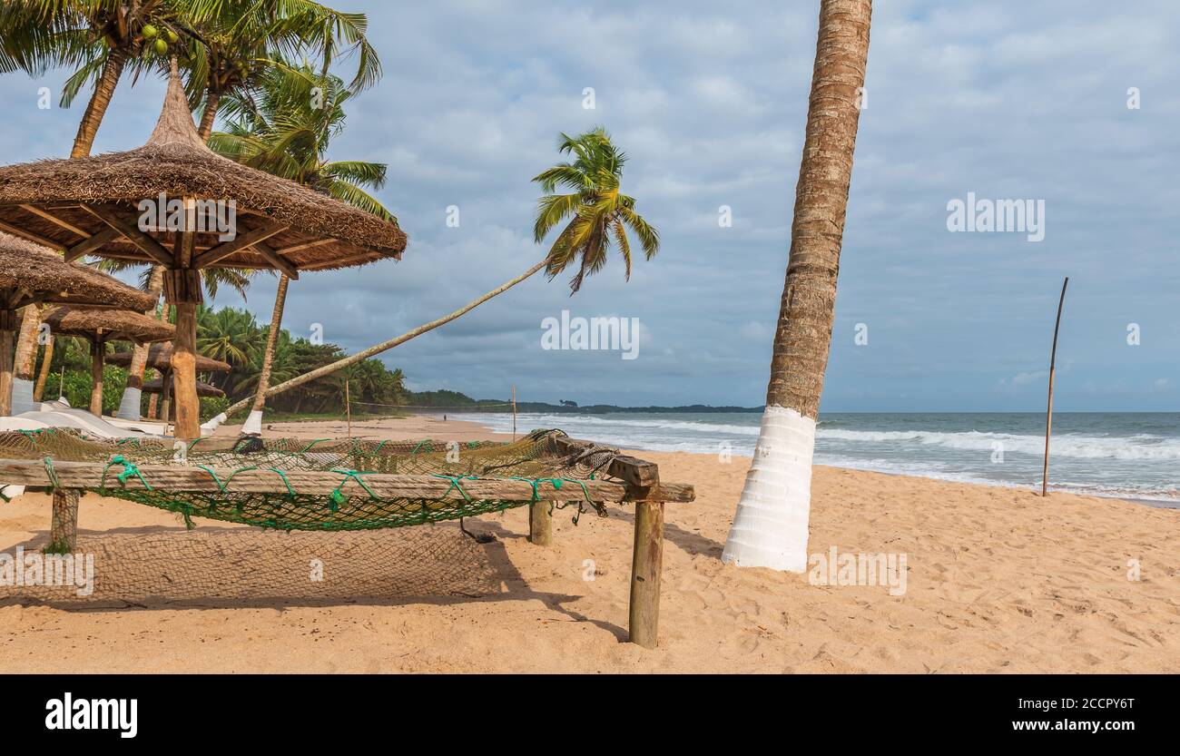 Tropischer Afrika-Strand mit Palmen und Liegestühlen, die leer stehen, liegt der Strand an Ghanas Goldküste Axim Stockfoto