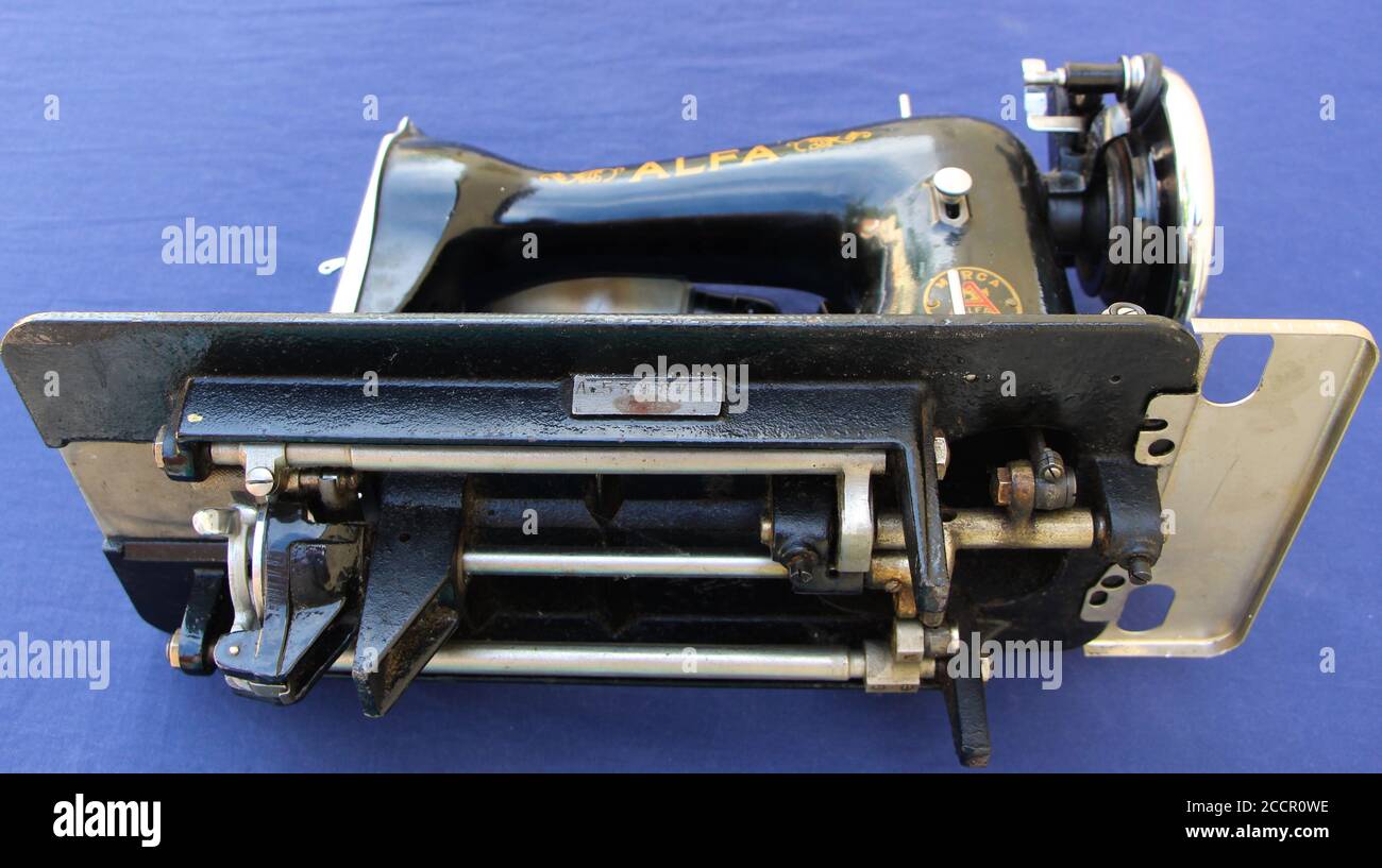 Alte Alfa elektrische Nähmaschine schwarz auf einem blauen gemalt Seitenansicht mit Stoffhintergrund und Mechanismus darunter Stockfoto