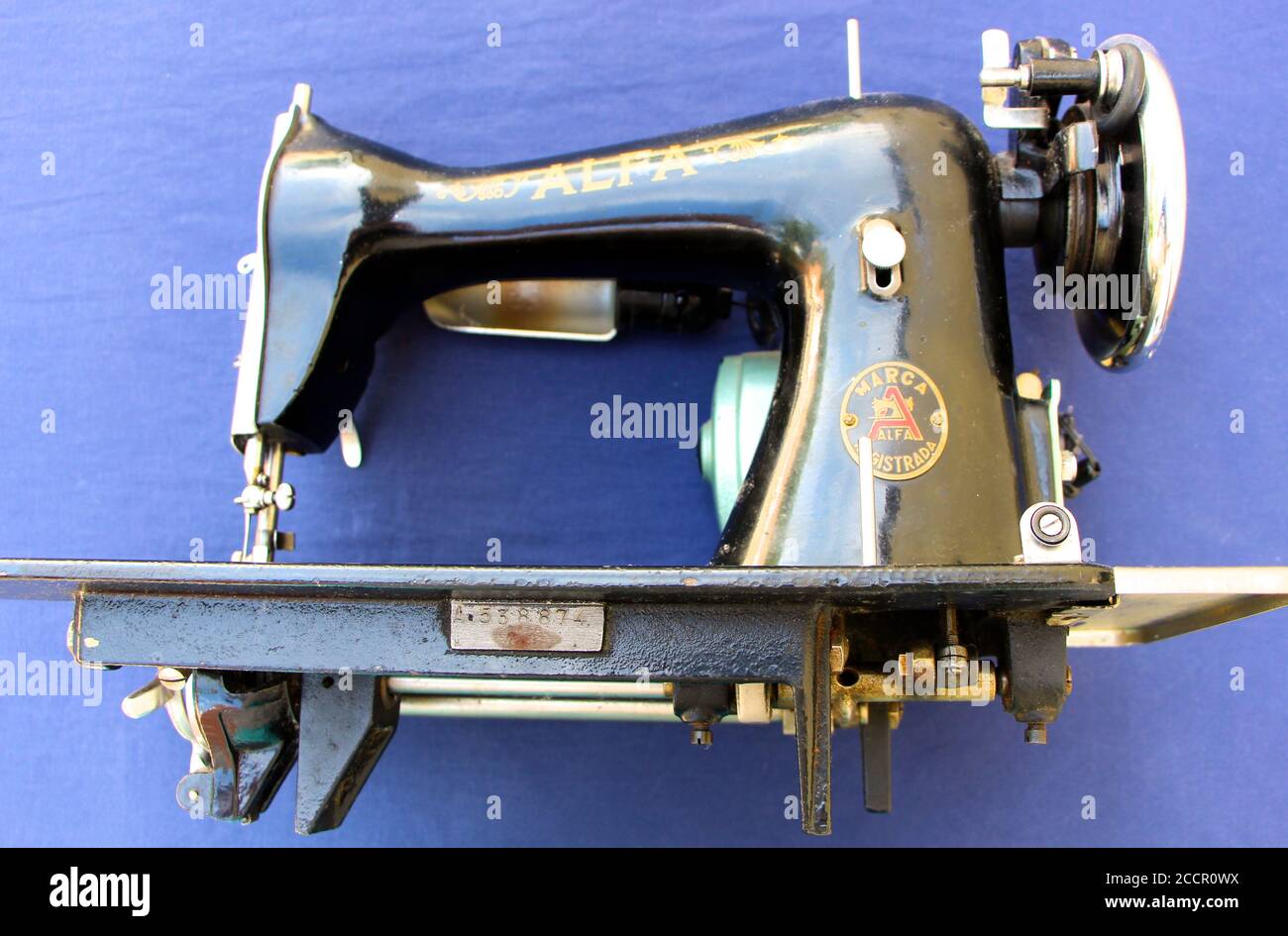 Alte Alfa elektrische Nähmaschine schwarz auf einem blauen gemalt Seitenansicht mit Stoffhintergrund und Mechanismus darunter Stockfoto