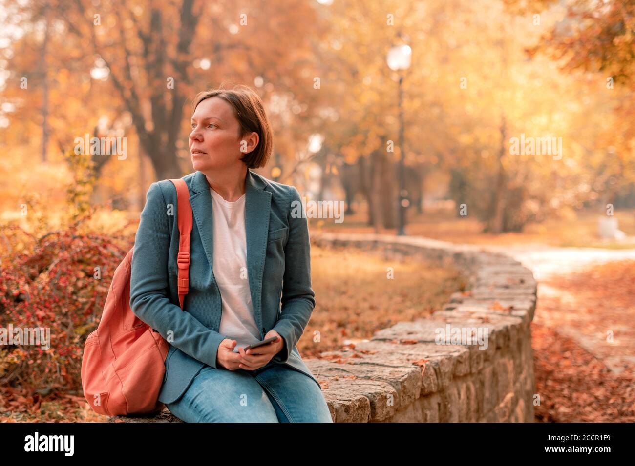 Geschäftsfrau sitzt und wartet auf jemanden im Herbst Park, selektive Fokus mit Kopieplatz Stockfoto