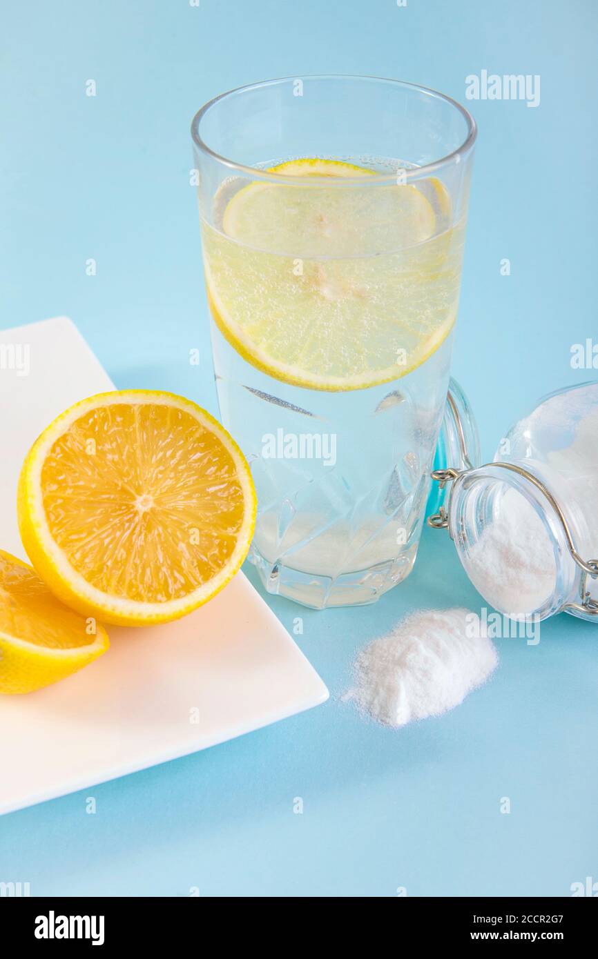 Backpulver in Trinkglas mit Wasser und Zitronensaft, gesundheitliche Vorteile für das Verdauungssystem Konzept. Hellblauer Hintergrund. Stockfoto
