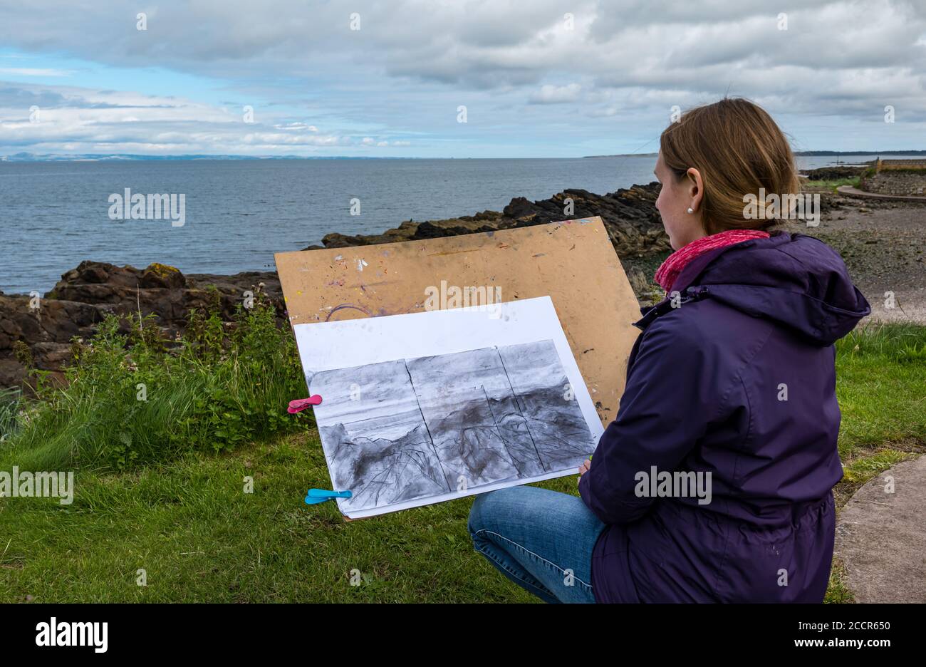 Cockenzie, East Lothian, Schottland, Großbritannien, 24. August 2020. Wetter in Großbritannien: Der Himmel erhellt sich für den ersten von einem 3-tägigen Skizzierworkshop, der von der Paintbox School of Art im Cockenzie House durchgeführt wird. Carrie Sanderson, eine Teilnehmerin der Skizzierklasse, betrachtet ihre Landschaftsskizze Stockfoto