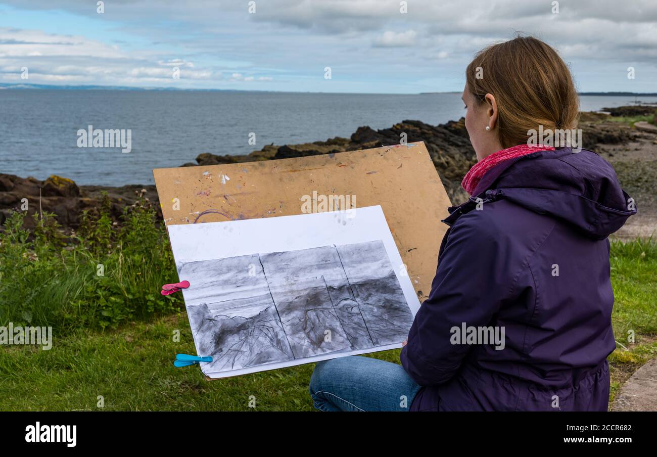 Cockenzie, East Lothian, Schottland, Großbritannien, 24. August 2020. Wetter in Großbritannien: Der Himmel erhellt sich für den ersten von einem 3-tägigen Skizzierworkshop, der von der Paintbox School of Art im Cockenzie House durchgeführt wird. Carrie Sanderson, eine Teilnehmerin der Skizzierklasse, betrachtet ihre Landschaftsskizze Stockfoto