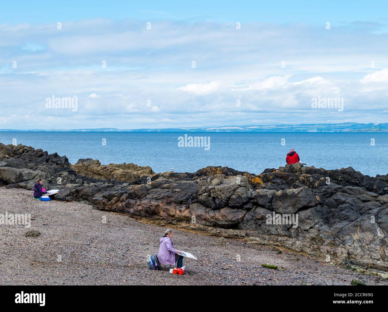 Cockenzie, East Lothian, Schottland, Großbritannien, 24. August 2020. Wetter in Großbritannien: Der Himmel erhellt sich für den ersten von einem 3-tägigen Skizzierworkshop, der von der Paintbox School of Art im Cockenzie House durchgeführt wird. Menschen sitzen auf den Felsen und am Strand einer kleinen Bucht, um die Landschaft in einer Skizzierstunde zu skizzieren Stockfoto