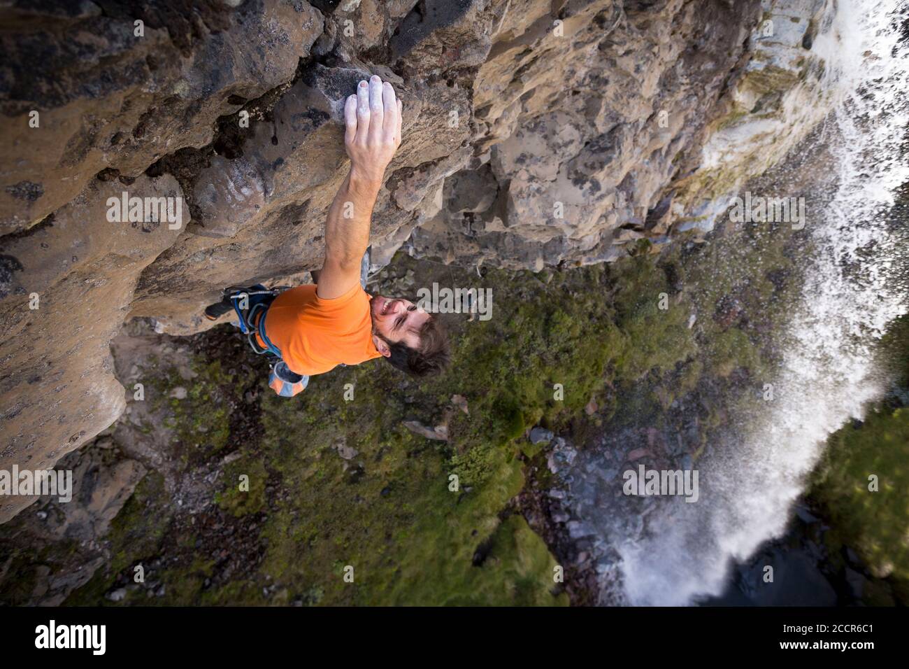 Ein Felskletterer, der eine steile Klippe neben einem Wasserfall bei White Falls, Mount Ruapehu, Tongariro National Park, Neuseeland aufsteigt Stockfoto