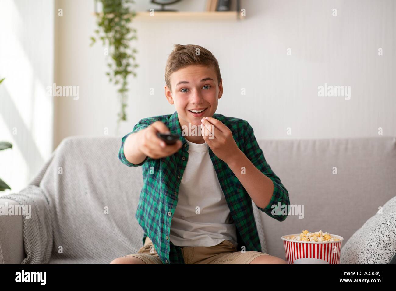 Emotionaler Teenager, der zu Hause Fernsehen und Popcorn essen kann Stockfoto