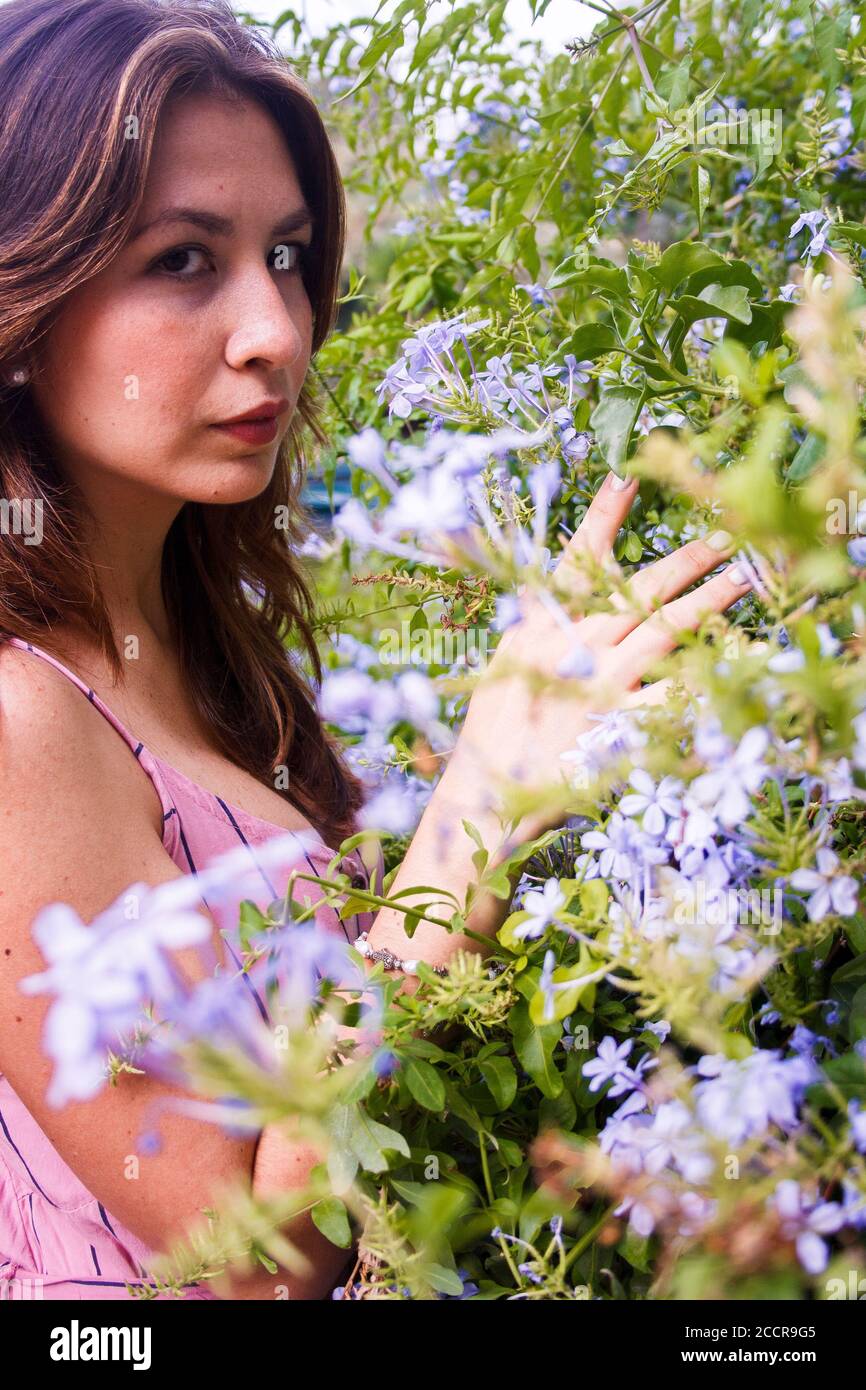 Junge Frau beobachten Wildblumen und Blick auf die Kamera. Mittlere Nahaufnahme. Vertikale Ansicht. Stockfoto