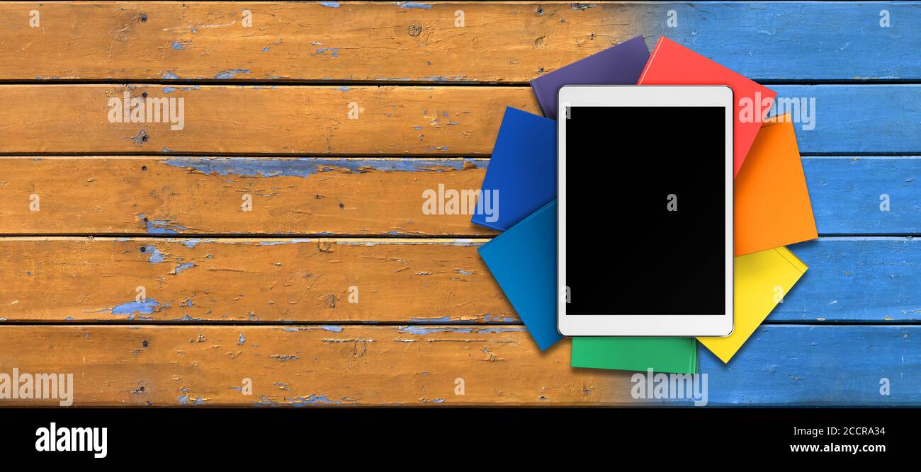 Tablet, Bücher in Regenbogenfarben auf dem Tisch von den alten Brettern, Vorderansicht Stockfoto