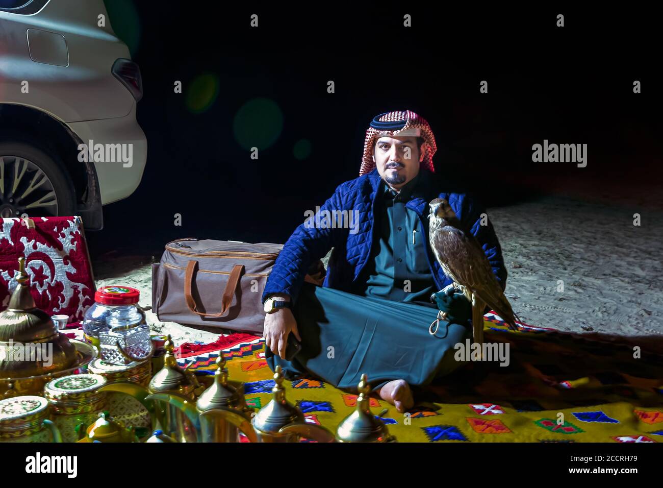 Saudi-arabischer Mann hält Falken in der Hand in der Wüste Nacht. Al-Sarar, Saudi-Arabien. Stockfoto