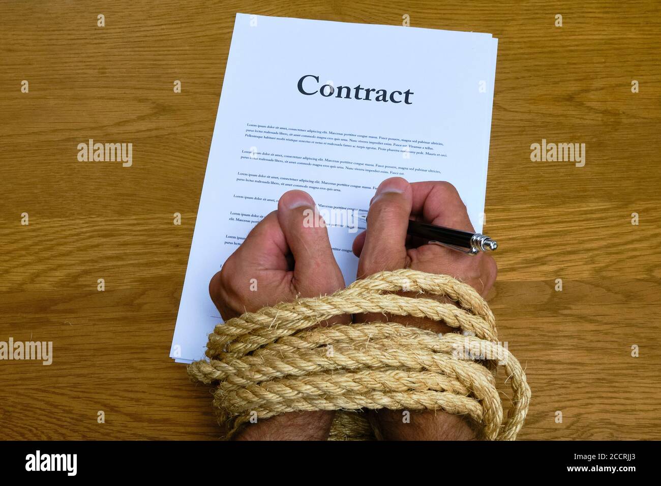 Vertrag und gebunden Hände halten Stift bereit zu unterschreiben. Hände gebunden während der Unterzeichnung unlauteren Vertrags. Vertrag schränkt die Freiheit des Mitarbeiters ein. Lorem Ipsum-Text Stockfoto