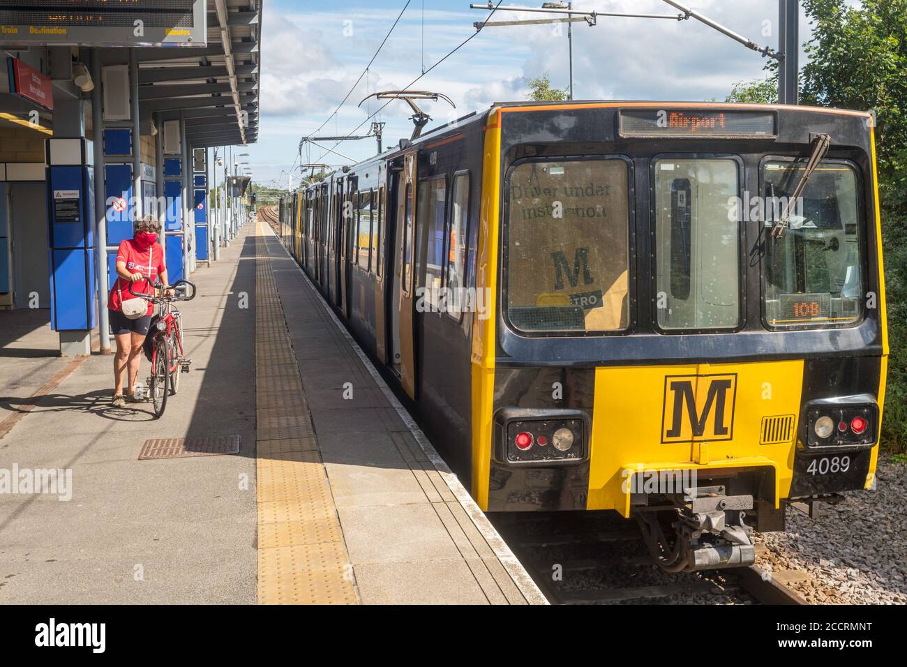 Ältere Radfahrerin mit Gesichtsmaske und Fahrrad auf Tyne und Metro South Hylton Station, Nordostengland, Großbritannien Stockfoto