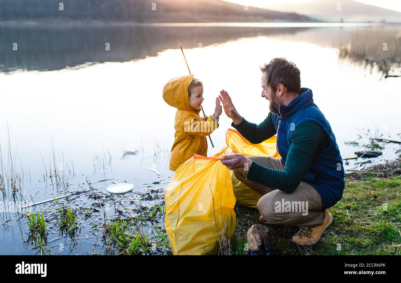 Vater mit kleiner Tochter sammeln Müll im Freien in der Natur, plogging Konzept. Stockfoto