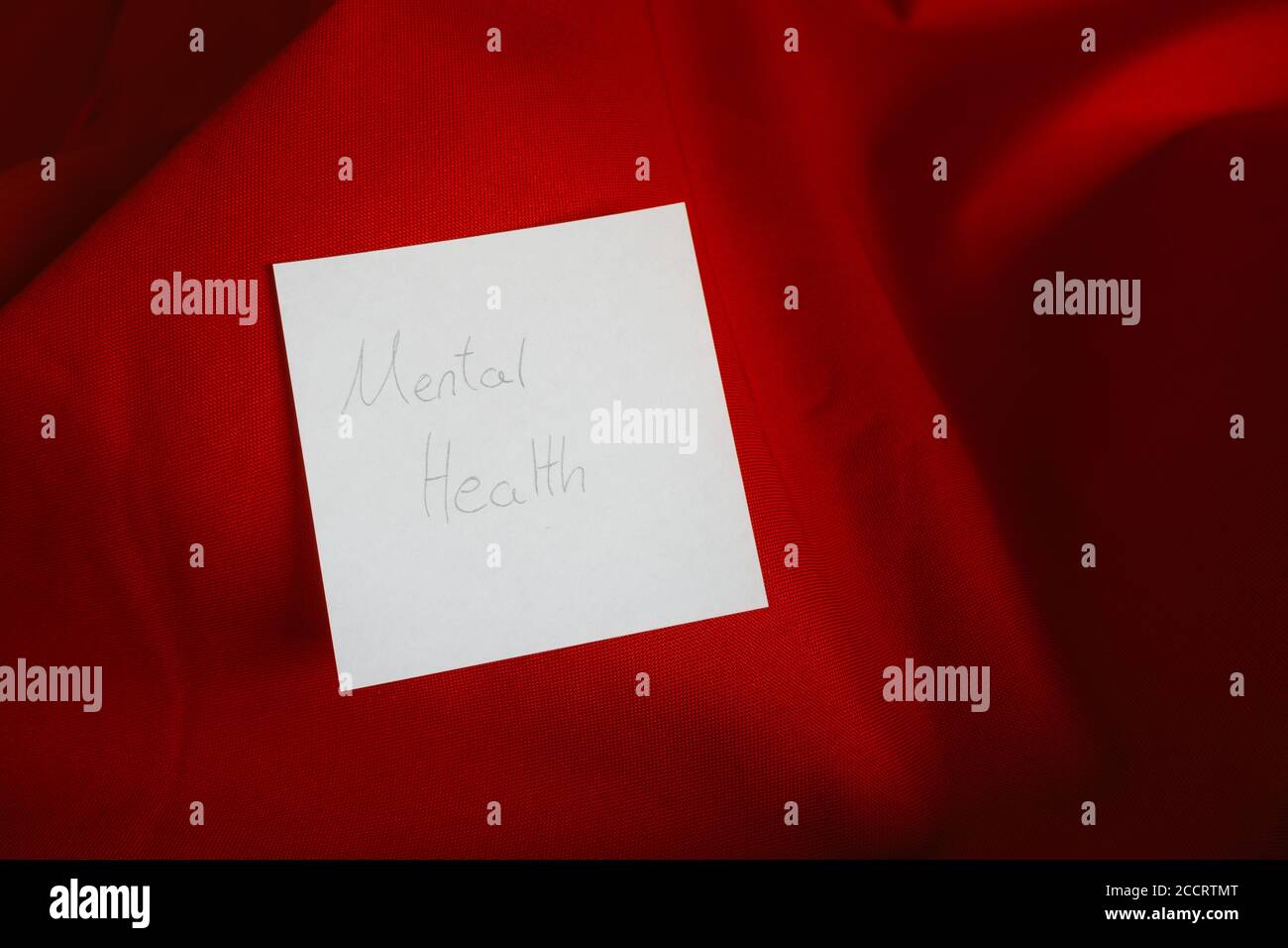 Eine Notiz mit der Aussage „mentale Gesundheit“, die auf einem roten Feld liegt Hintergrund Stockfoto