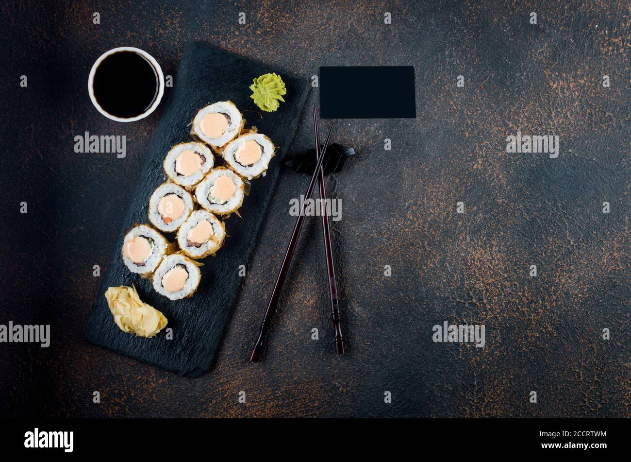 Maki-Brötchen auf Steinplatte mit Soßen, Ingwer und Wasabi Stockfoto
