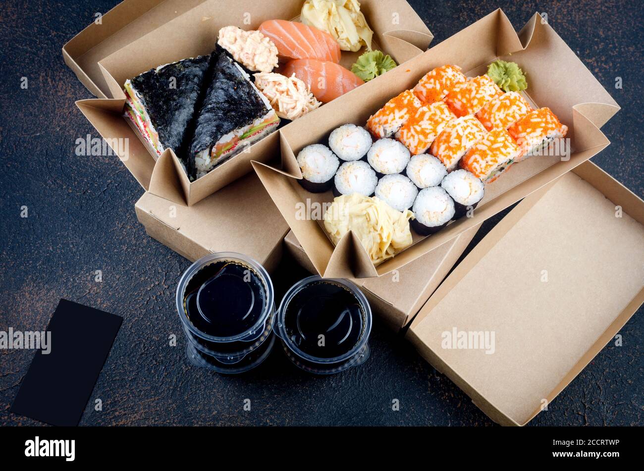 Leckere Sushi-Rollen in Einweg-Kraftpapier-Boxen, Saucen, Essstäbchen. Essen zum Mitnehmen oder zur Lieferung Stockfoto