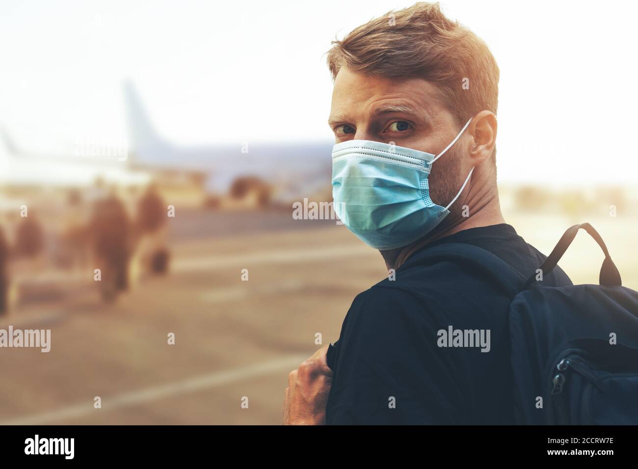 Reise während der Coronavirus-Pandemie - junger Mann trägt schützendes Gesicht Maske und Bordflugzeug am Flughafen Stockfoto