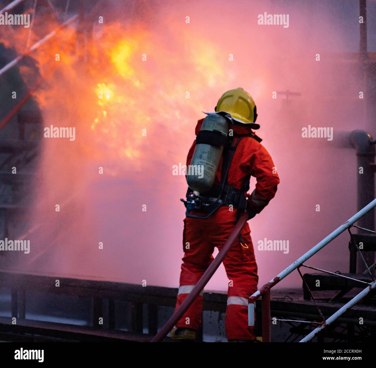 Feuerwehrmann mit Wasser Nebel Art Feuerlöscher zur Bekämpfung mit der Feuerflamme von Ölleitung Leck und Explosion auf Ölplattform und Erdgas sta Stockfoto