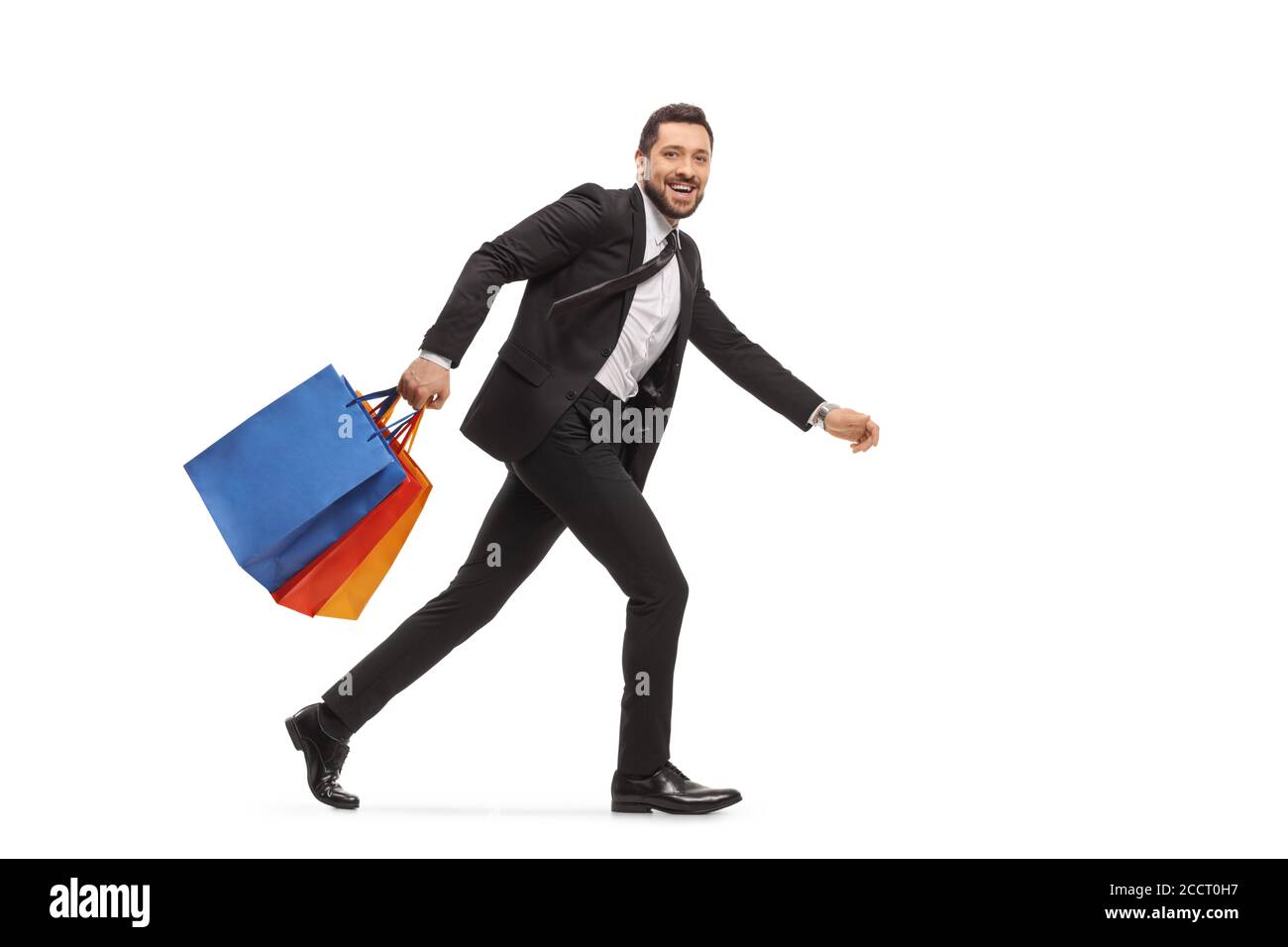 Mann in einem Anzug, der mit isolierten Einkaufstaschen läuft Weißer Hintergrund Stockfoto