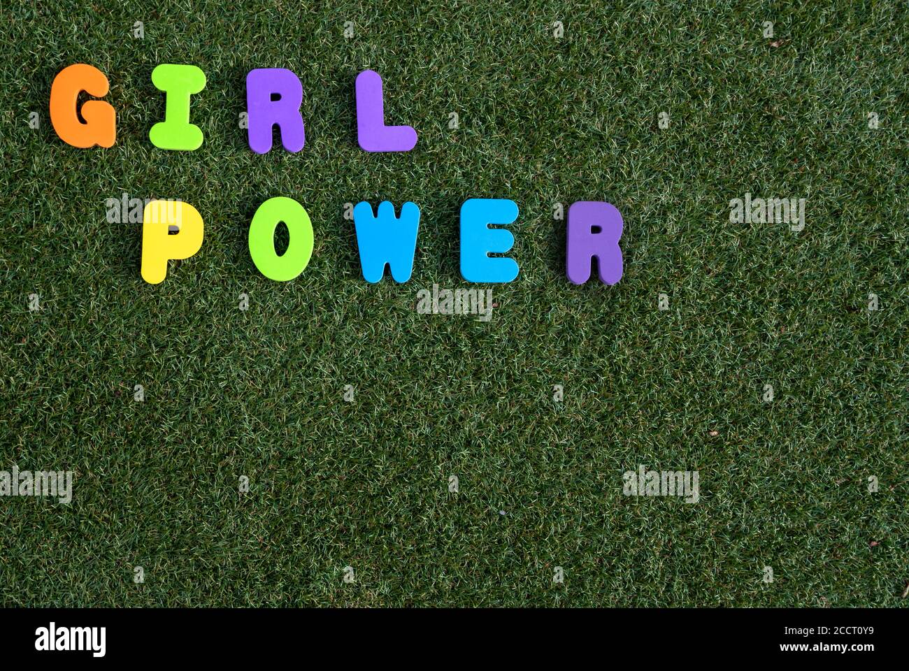 Mädchen macht Dinkel auf grünem Gras Hintergrund mit bunten Briefe Stockfoto