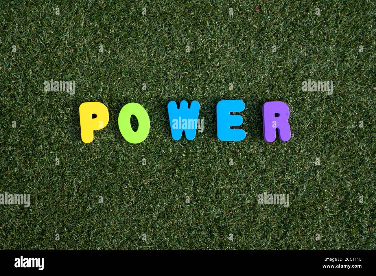 Power Dinkel auf grünem Gras Hintergrund mit bunten Buchstaben Stockfoto