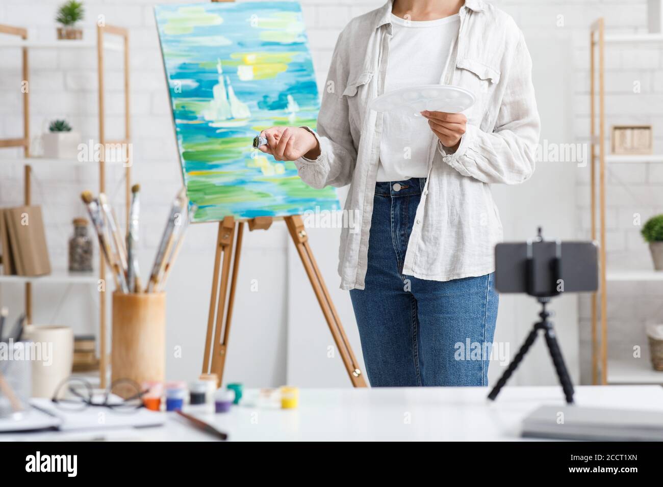 Malerei und moderne Technik. Mädchen mit Pinsel und Farben zu Hause malen Stockfoto