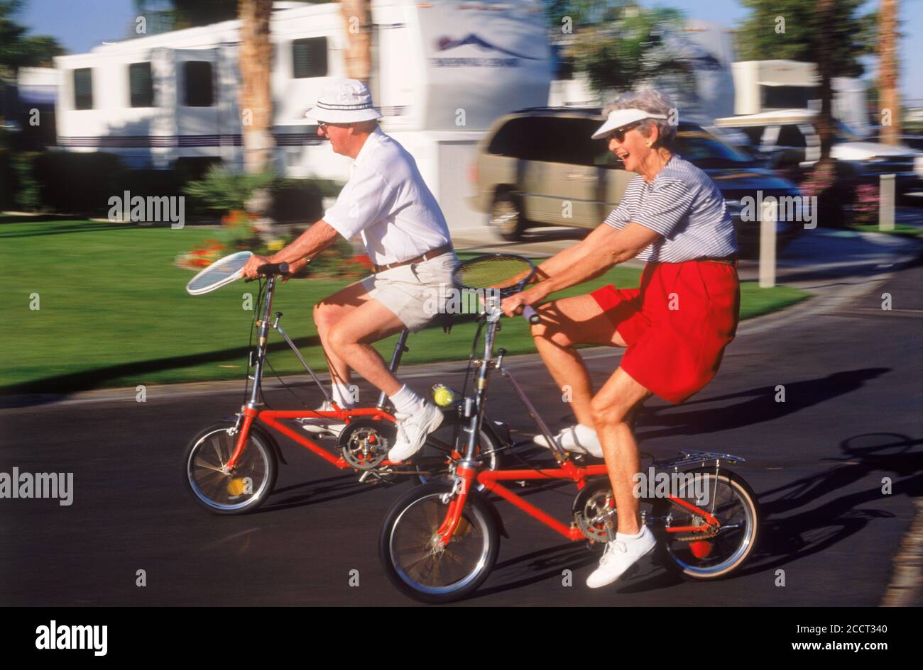 Ehepaar im Ruhestand Radfahren mit Tennisschlägern in Cathedral City in der Nähe von Palm Springs in Kalifornien Wüste Stockfoto