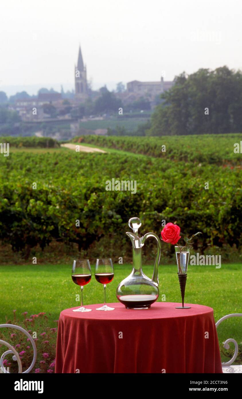 Französischer Wein und Dekanter und Rose mit Weinbergen und Saint Emilion Dorfkirche dahinter Stockfoto