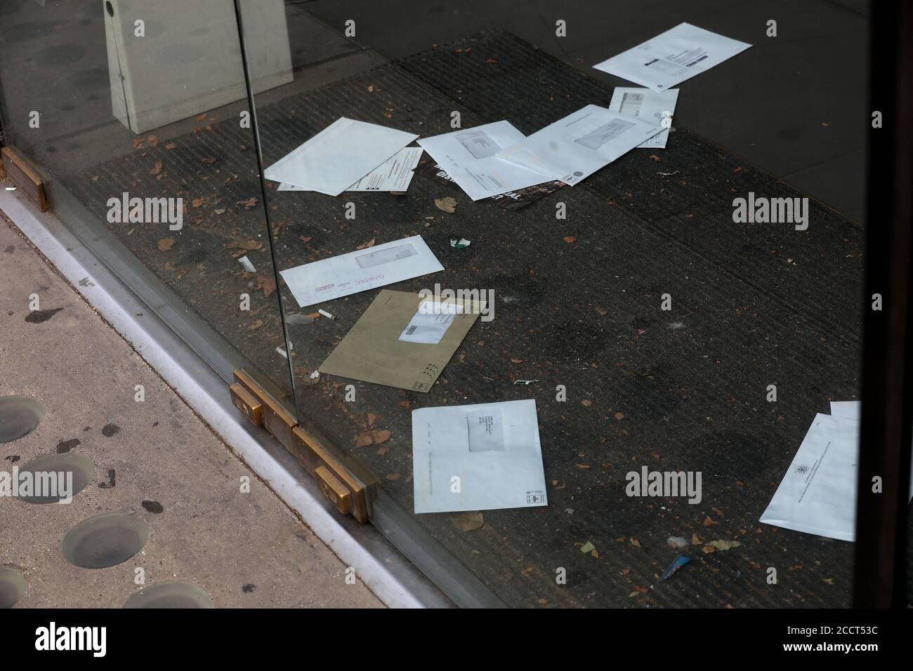 Briefe und Rechnungen stapeln sich auf der Türmatte eines geschlossenen Ladens an der Brompton Road, London, Großbritannien. Stockfoto