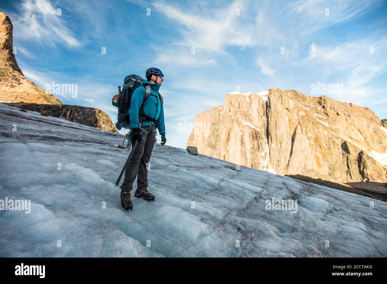 Rucksacktourist, der auf dem Gletscher unterhalb des Berggipfels steht. Stockfoto