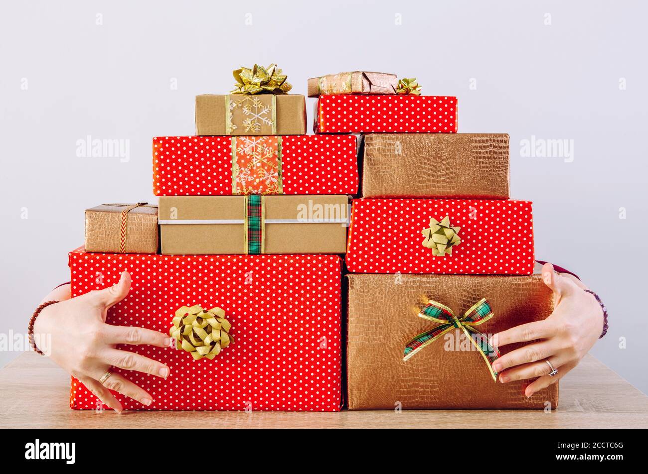 Person horten roten kalten Farben Boxen Weihnachtsgeschenke. Bewachende Hände, die hinter einem großen Geschenkstapel stehen. Stockfoto