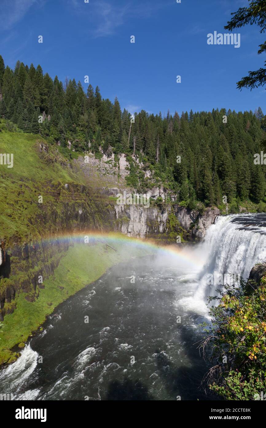 Ein Regenbogen im Nebel der Upper Mesa Falls Es stürzt über eine Klippe in die zerklüftete Wildnis von Henrys Fork des Snake River entlang der Mesa Falls Stockfoto