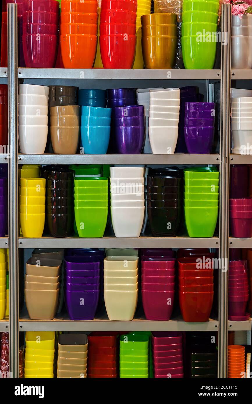 Blumentöpfe aus Kunststoff in verschiedenen Farben auf den Regalen Stockfoto