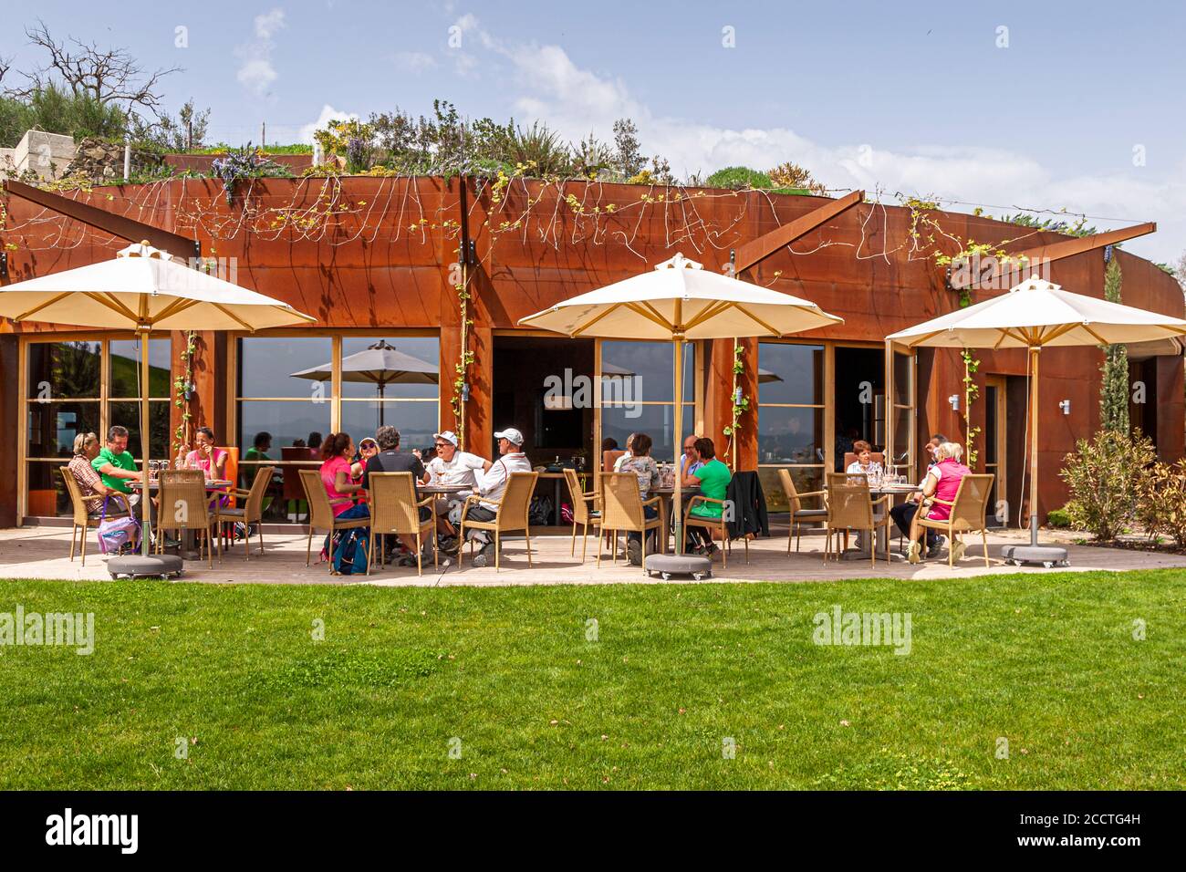 Das Restaurant Tenuta Sanoner heißt Gäste zum Mittagessen auf seiner panoramischen Terrasse in der Nähe von Bagno Vignoni, Val d'Orcia, Italien, willkommen, wobei seine corten-stählerne Fassade die Weinberge unten überblickt. Stockfoto