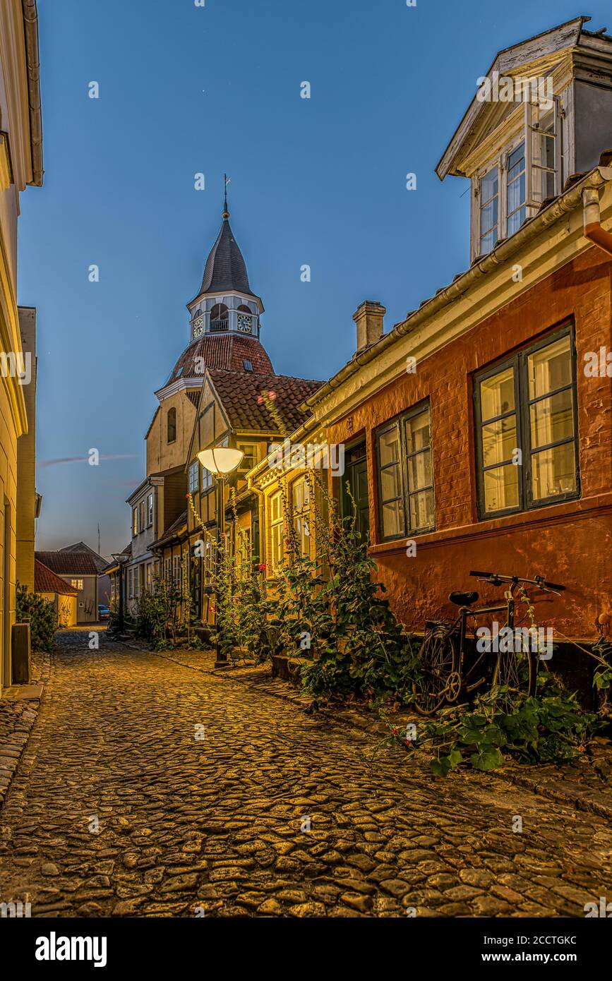 Malerische Gasse mit Kopfsteinpflaster und Hollyhocks in der goldenen Stunde, Faaborg, Dänemark, 17. August 2020 Stockfoto