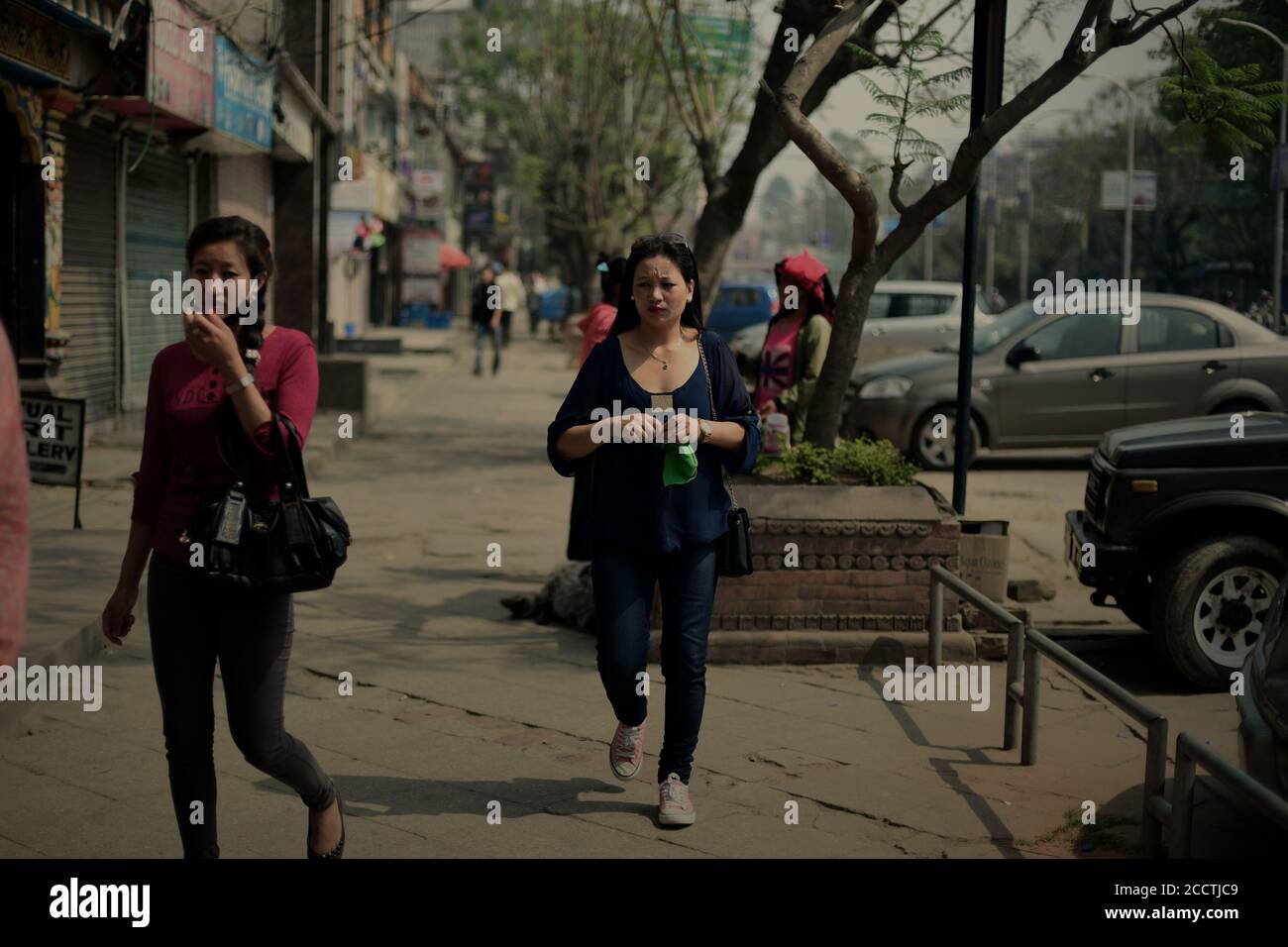 Frauen, die auf dem Gehweg einer Hauptstraße in der Innenstadt von Kathmandu, Nepal, laufen. Stockfoto