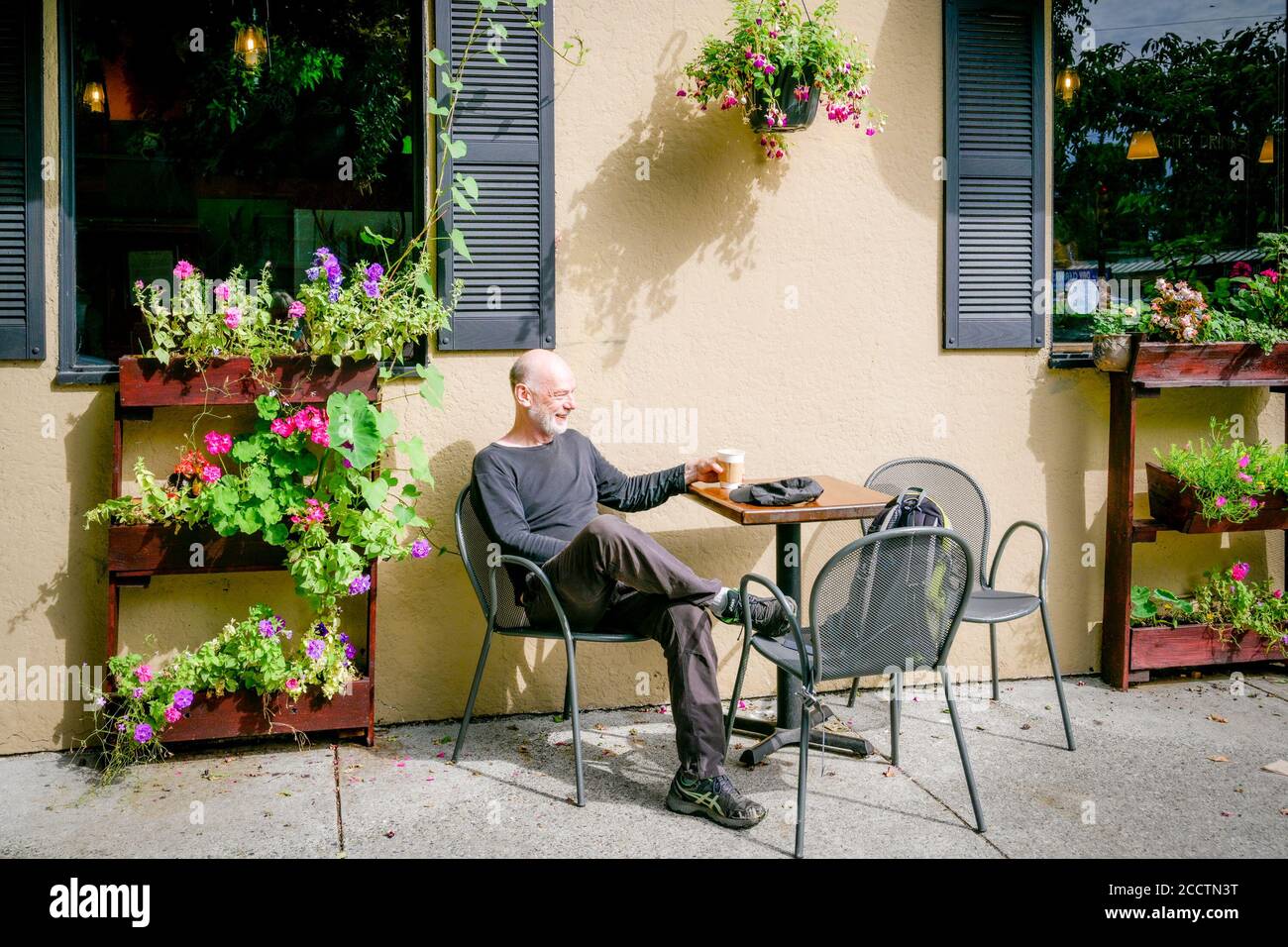 Mann, der die Terrasse im Artistry Coffee House and Bistro, Kitsilano, Vancouver, British Columbia, Kanada, genießt Stockfoto