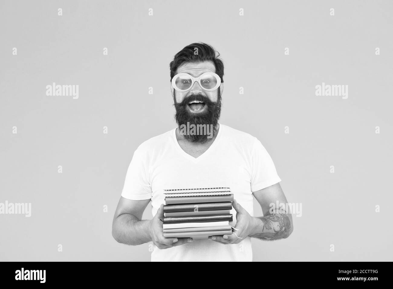 Hartes Semester. Absolvent der Universität. Zurück zur Schule. Reifer Schüler präsentiert einige Bücher. Büro-Zubehör. Wie man Übung. Helle Ideen für das Studium. Glücklicher Mann in einer Brille mit Notizbuch. Stockfoto