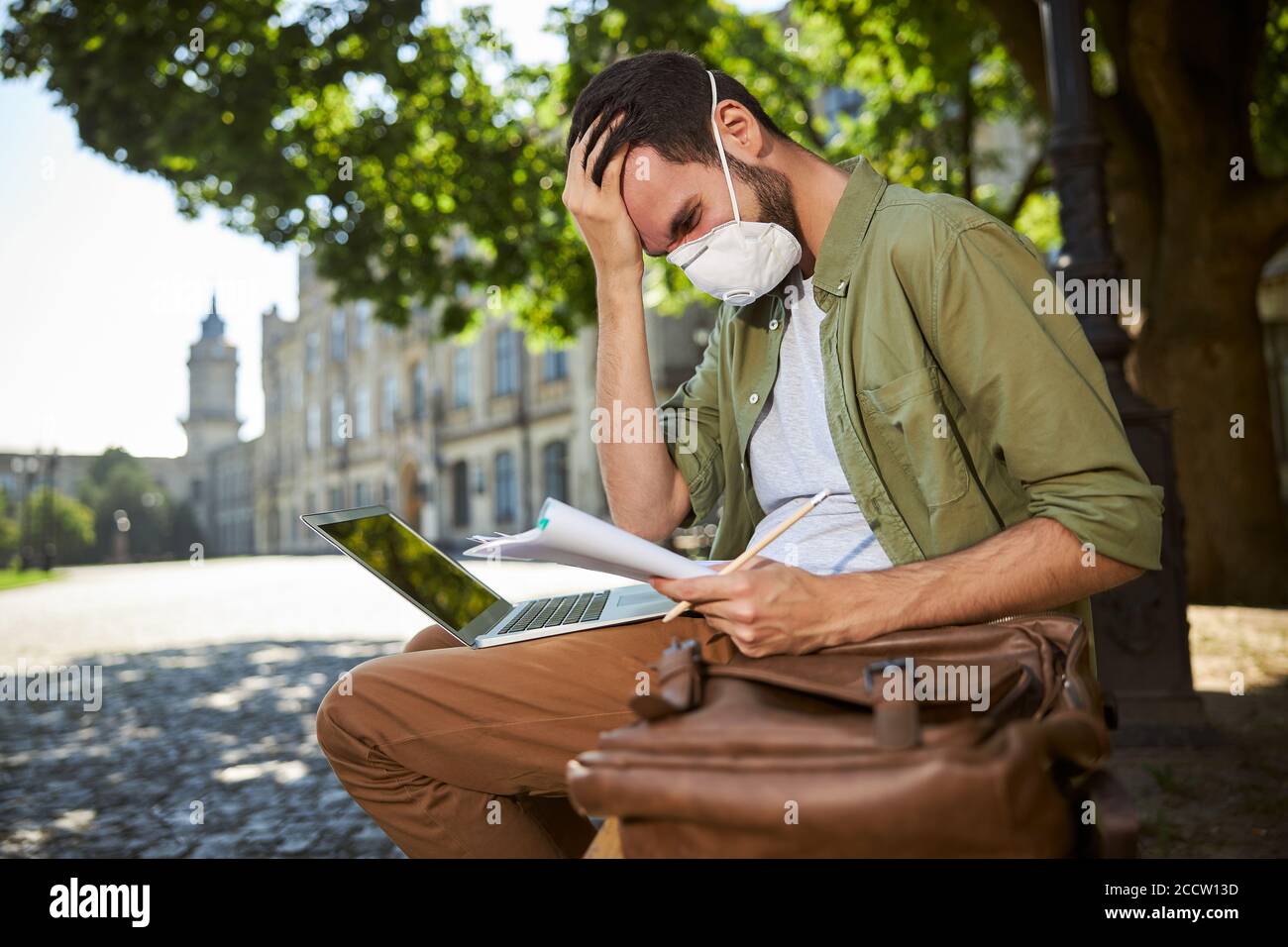 Junger Mann in einer Gesichtsmaske studieren im Freien Stockfoto