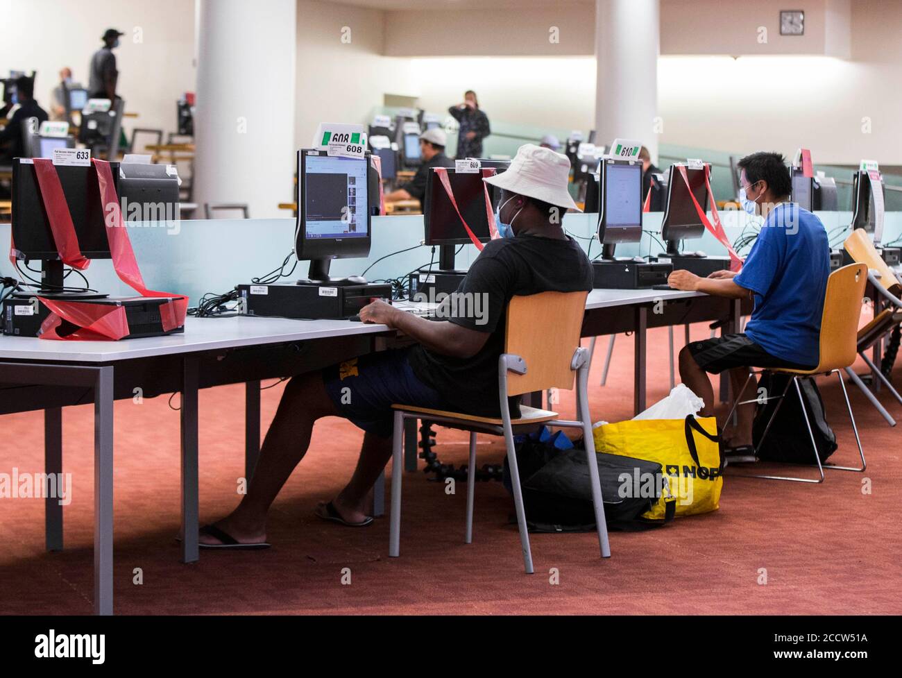 Toronto, Kanada. August 2020. Menschen, die Gesichtsmasken tragen, halten eine physische Distanz, da sie am 24. August 2020 Computer in einer Bibliothek in Toronto, Kanada, benutzen. Die dritte Phase des Plans zur Wiedereröffnung der Toronto Public Library begann am Montag. Menschen können in Bibliotheksbranchen zurücktreten, um Gegenstände zu durchsuchen und auszuleihen, WLAN zu nutzen und auf Schnellreferenzdienste zuzugreifen sowie zu arbeiten oder zu studieren und zu drucken, zu scannen oder zu fotokopieren. Quelle: Zou Zheng/Xinhua/Alamy Live News Stockfoto