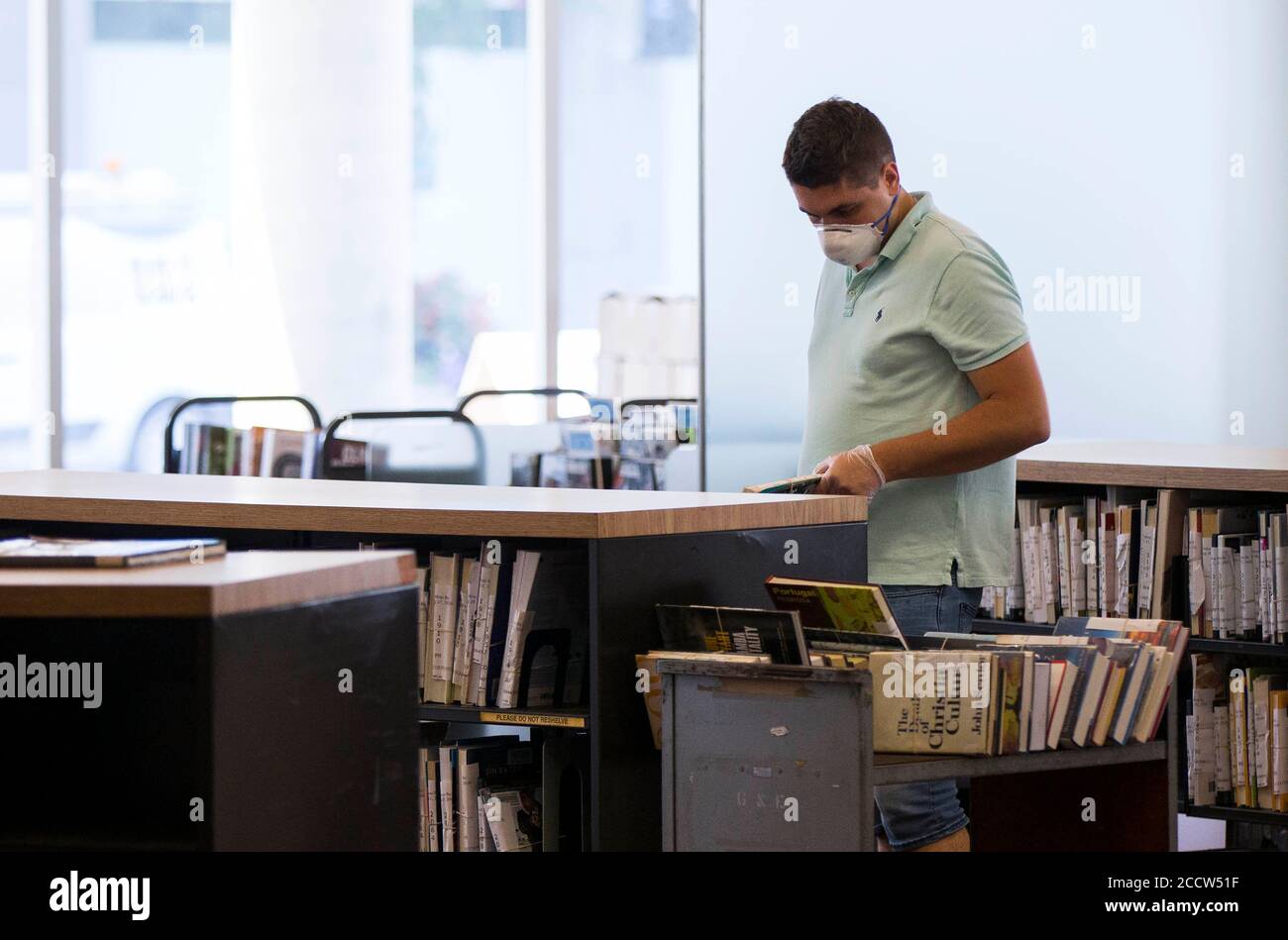 Toronto, Kanada. August 2020. Ein Mitarbeiter mit Gesichtsmaske arrangiert am 24. August 2020 Bücher in einer Bibliothek in Toronto, Kanada. Die dritte Phase des Plans zur Wiedereröffnung der Toronto Public Library begann am Montag. Menschen können in Bibliotheksbranchen zurücktreten, um Gegenstände zu durchsuchen und auszuleihen, WLAN zu nutzen und auf Schnellreferenzdienste zuzugreifen sowie zu arbeiten oder zu studieren und zu drucken, zu scannen oder zu fotokopieren. Quelle: Zou Zheng/Xinhua/Alamy Live News Stockfoto