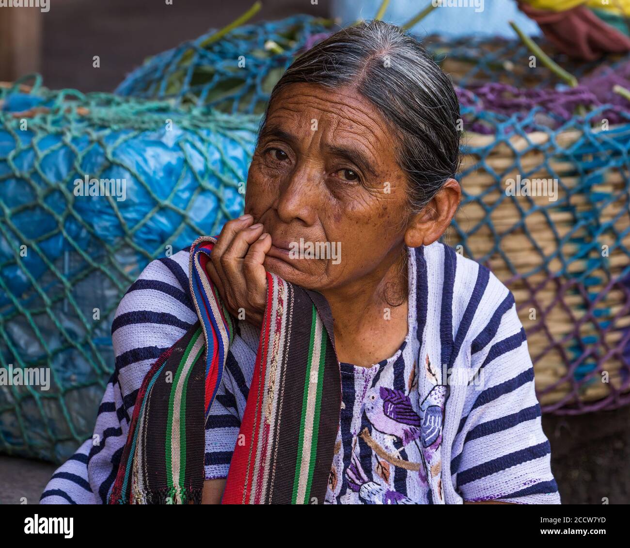 Eine ältere Tzutujil Maya Frau in traditioneller Kleidung verkauft Produkte auf dem Wochenmarkt in Santiago Atitlan, Guatemala. Stockfoto