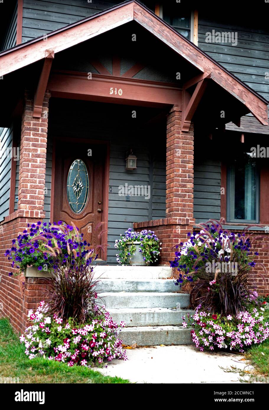 Die Treppe und der Eingang sind mit Petunien in den Farben Rosa, Weiß und Lila dekoriert. Fergus Falls, Minnesota, USA Stockfoto